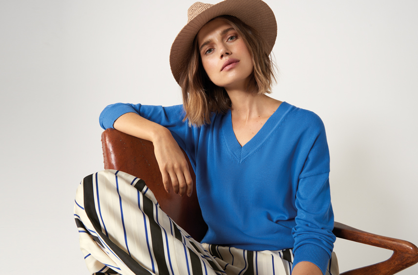 Woman wearing a blue jumper, striped pants and a hat